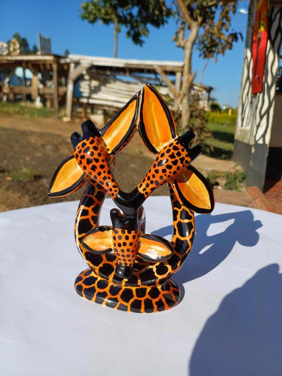 A hand-painted orange-and-black soapstone sculpture of a giraffe family
