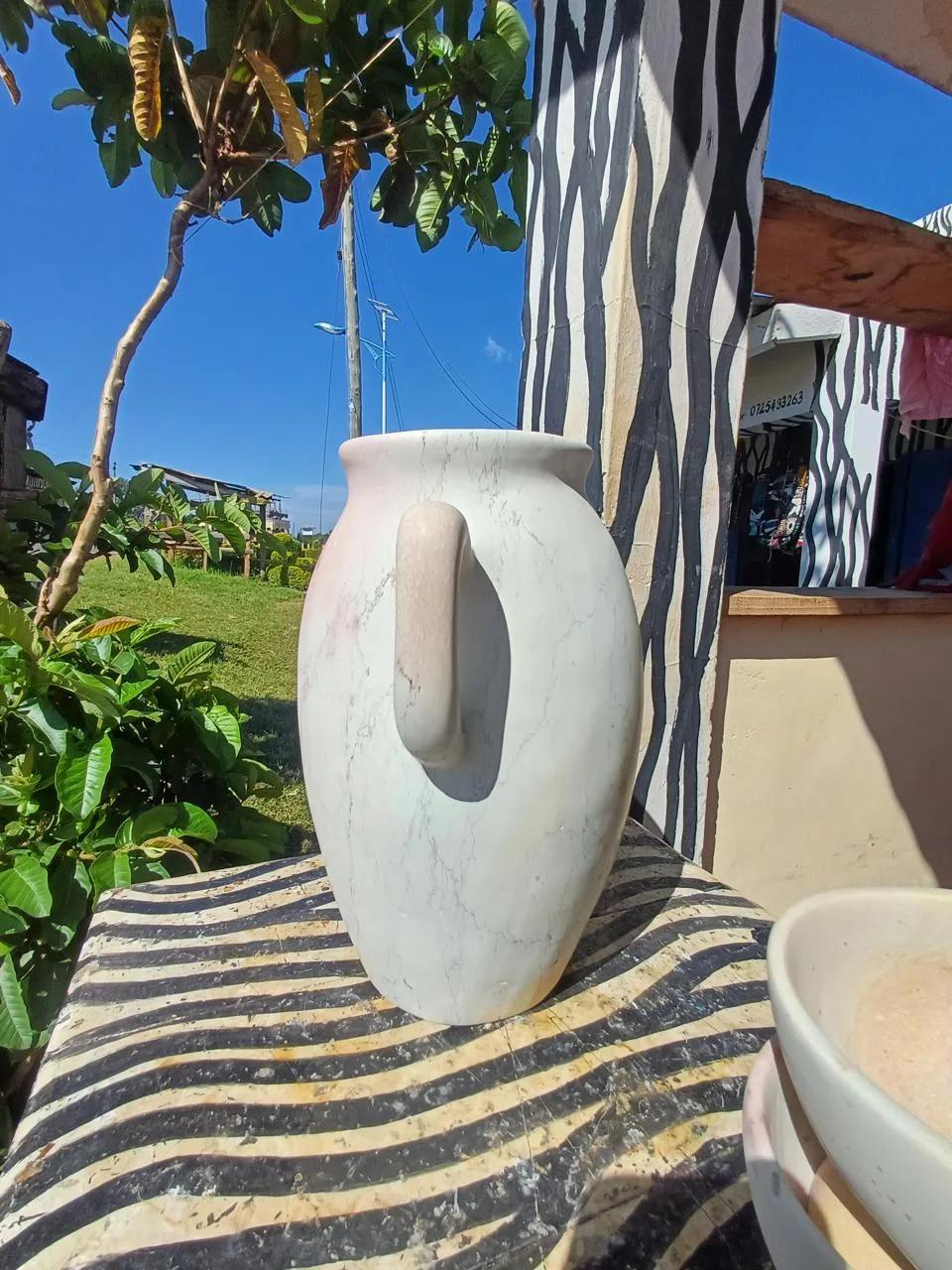 A white Kisii soapstone jug with natural grey veins and a pink-toned handle