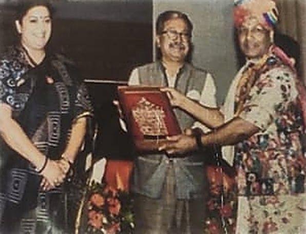 A member of the Marotia family, in a turban, receiving a framed award